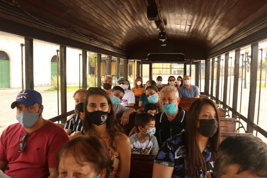 Pessoas sentadas dentro do bonde turístico #paratodosverem