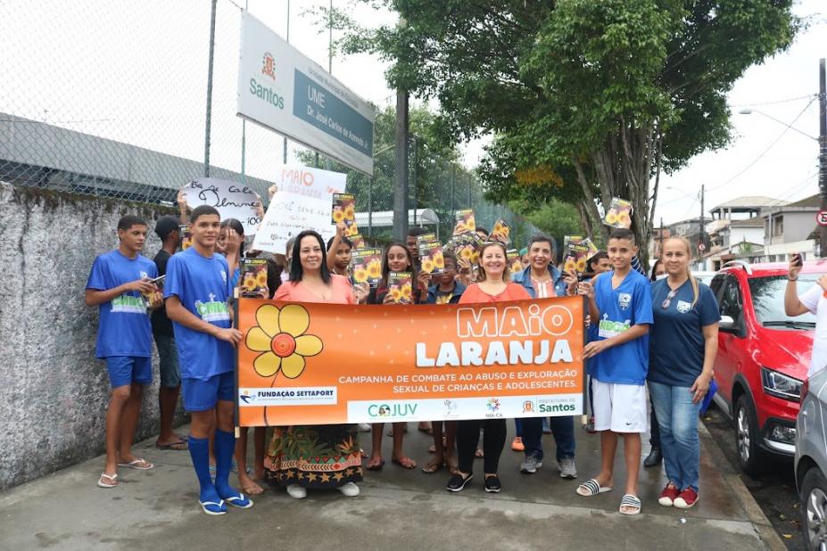 alunos na rua em frente a escola mostram cartaz da campanha #paratodosverem