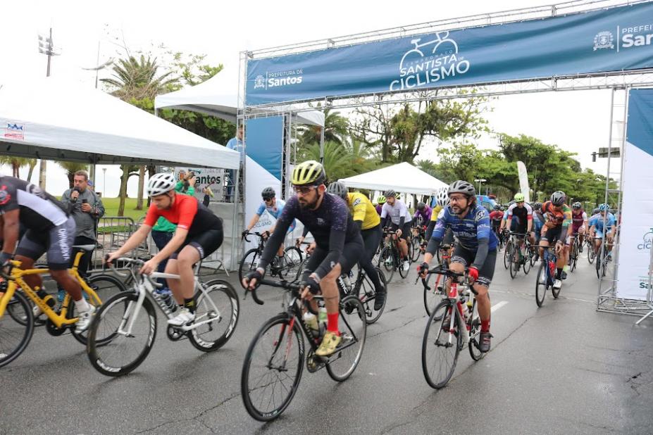 Largada da prova com ciclistas abaixo do portal. Prova é na orla. #paratodosverem