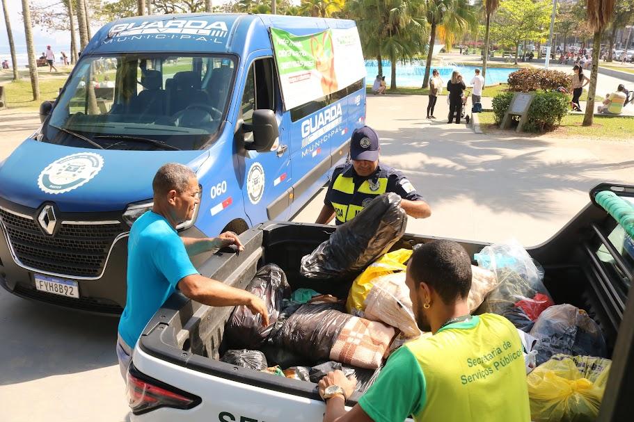 van da guarda municipal na orla ao lado de caminhonete já com vários sacos de roupas. #paratodosverem