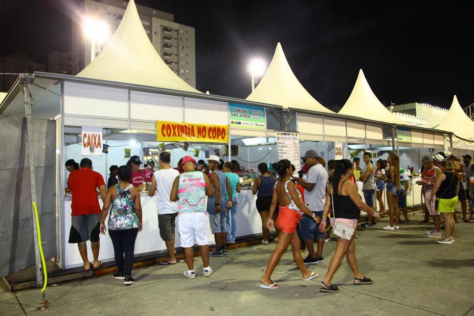 tendas para venda de lanches com pessoas circulando em torno. #paratodosverem 