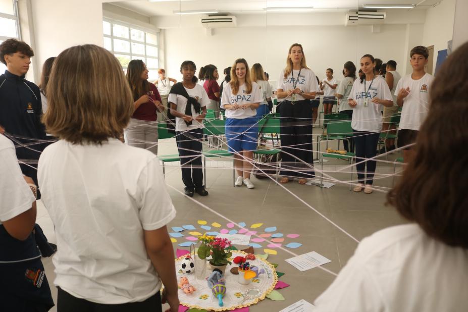 jovens formam rede de conexão com fios de lã. #paratodosverem 