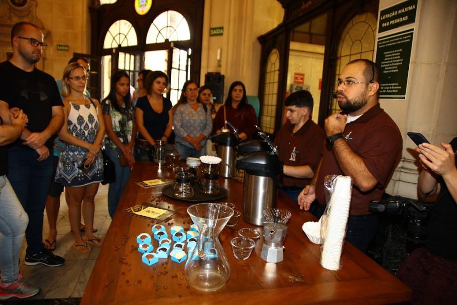 pessoa fala com mesa com café e doces para outras pessoas #paratodosverem