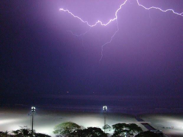 praia à noite com vista da faixa de arreia em primeiro plano e o mar ao fundo. Raios caem. #paratodosverem