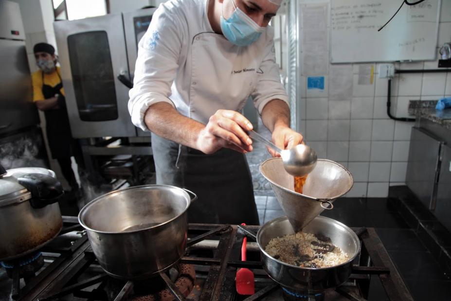 chefe de cozinha prepara prato e coloca o café líquido em risoto que está na panela. #paratodosverem