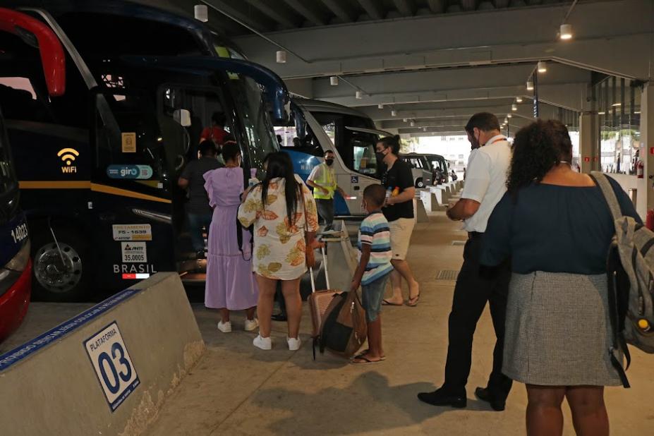 pessoas fazem fila para entrar em ônibus parado em baia na rodoviária. Há outros ônibus ao fundo. #paradodosverem