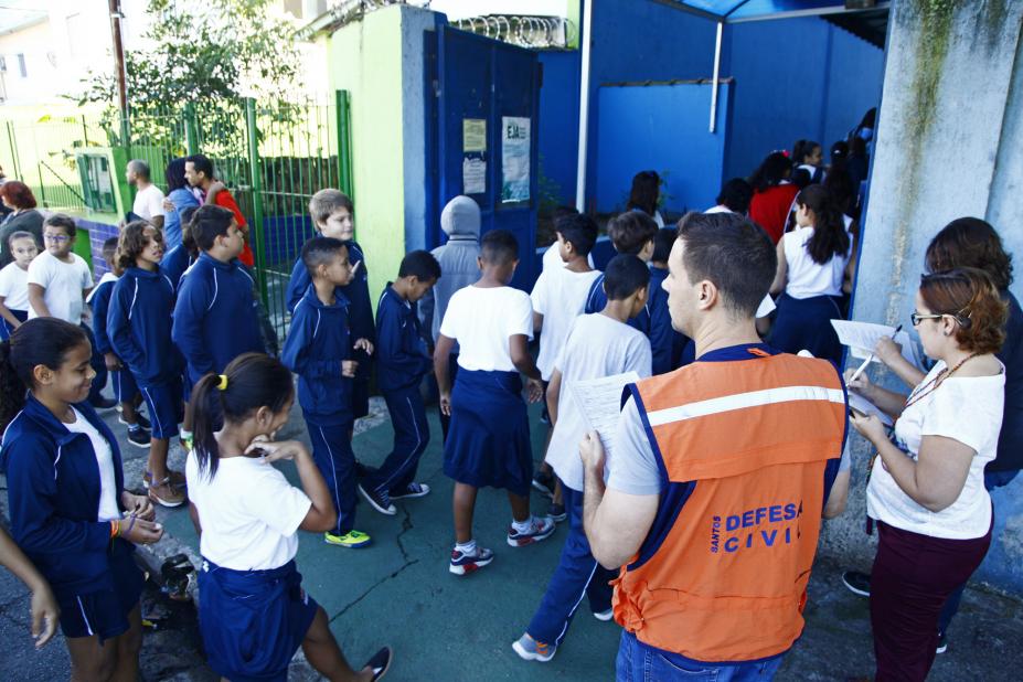 Crianças e pessoal de apoio da Defesa Civil nas dependências da escola. #Pracegover