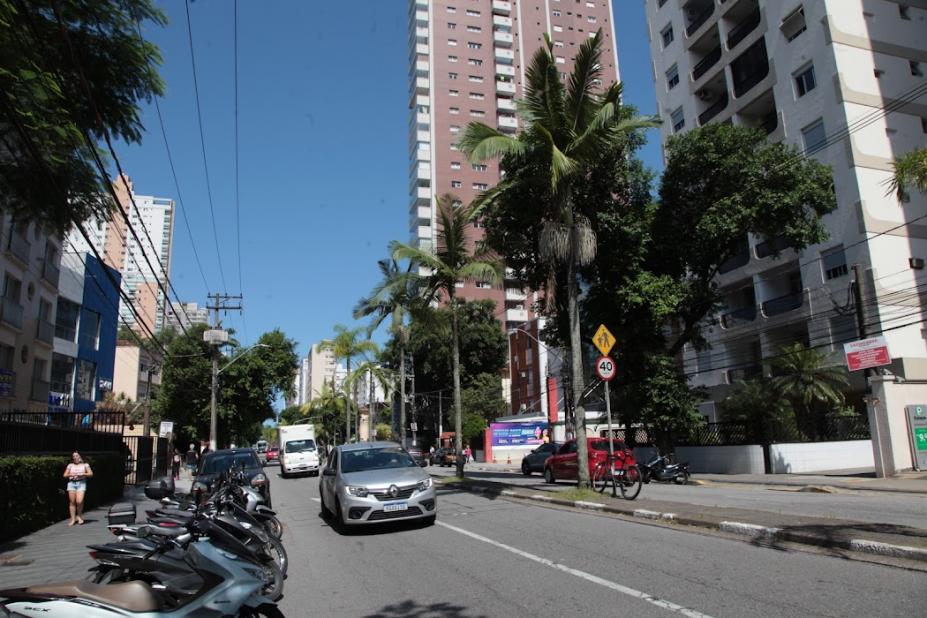 imagem da avenida com carros, motos estacionadas e prédios ao fundo #paratodosverem