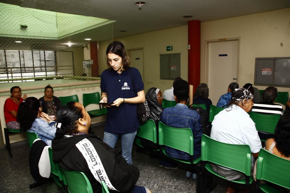 servidor da ouvidoria fala com pessoas sentadas em sala de espera #pracegover 