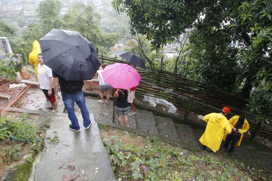 Equipe da defesa civil em morro junto a moradores. #Paratodosverem