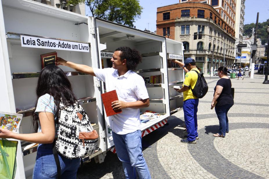 pessoas pegam livros no estande do projeto #pracegover 