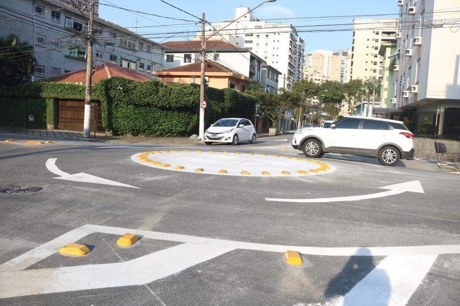 Rotatória implementada no solo com sinalização. Um carro faz o cruzamento e outro aguarda. #paratodosverem