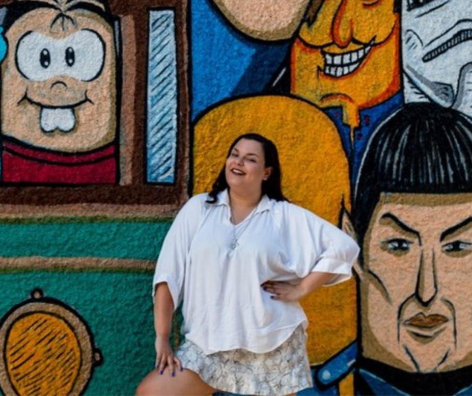 Sarah Campos posa para foto em frente a mural grafitado. #paratodosverem