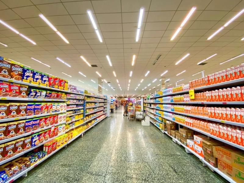 corredor de supermercado com gôndolas cheias de produtos dois dois lados. #paratodosverem 