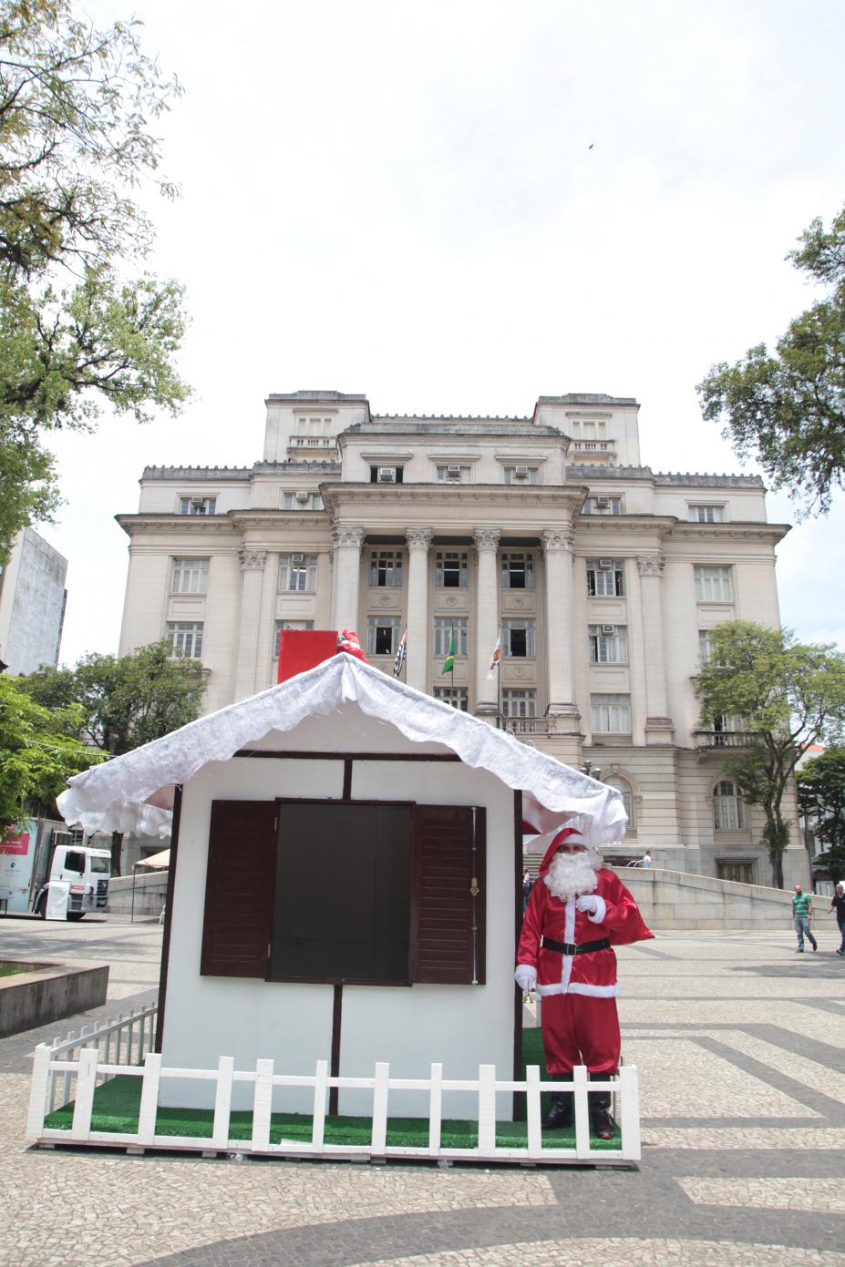 Casinha do Papai Noel em praça. O bom velhinho está do lado de fora. #Pracegover