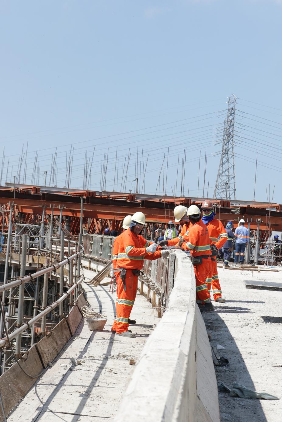 Construção do viaduto Piratininga. Homens estão trabalhando sobre trecho do viaduto. Eles estão próximos a um longo guarda-corpo. Estão visíveis estruturas metálicas. #Pracegover