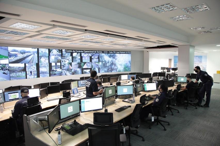Centro de controle operacional com vários computadores e várias telas com imagens das câmeras. #paratodosverem