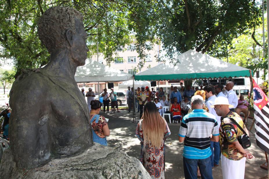Pessoas estão em círculo durante homenagem a Zumbi #pracegover 
