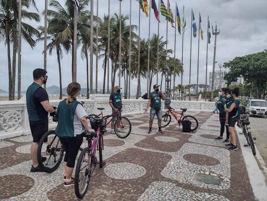 ciclista estão desmontados das bikes na praça das bandeiras. Umdeles fala ao grupo. #paratodosverem