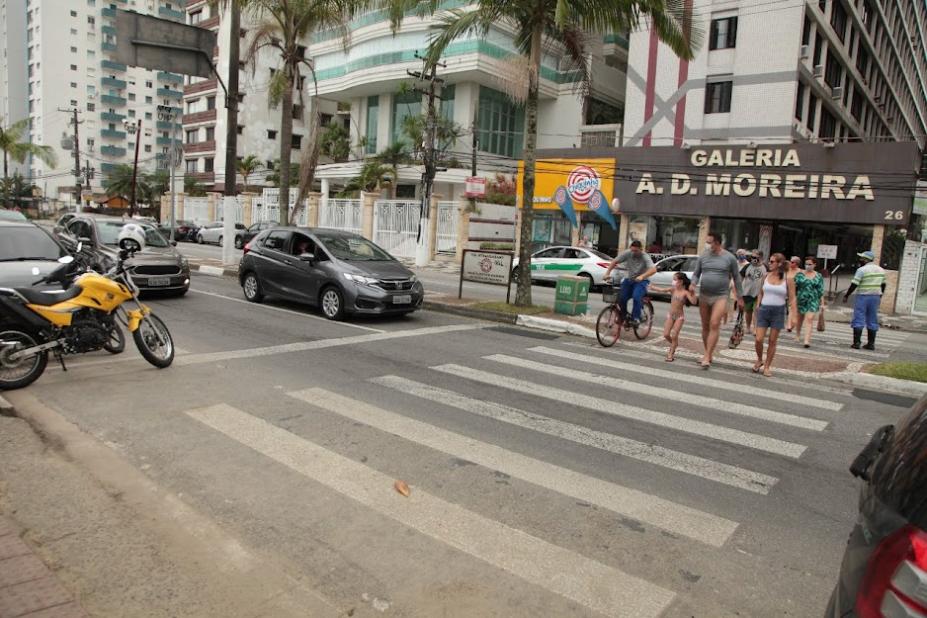 Pedestres atravessam em faixa na orla do Gonzaga em frente a veículos parados. #pratodosverem