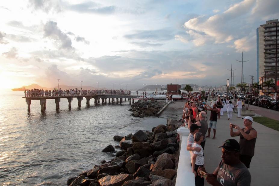 pessoas fotografando por do sol na ponta da praia #paratodosverem
