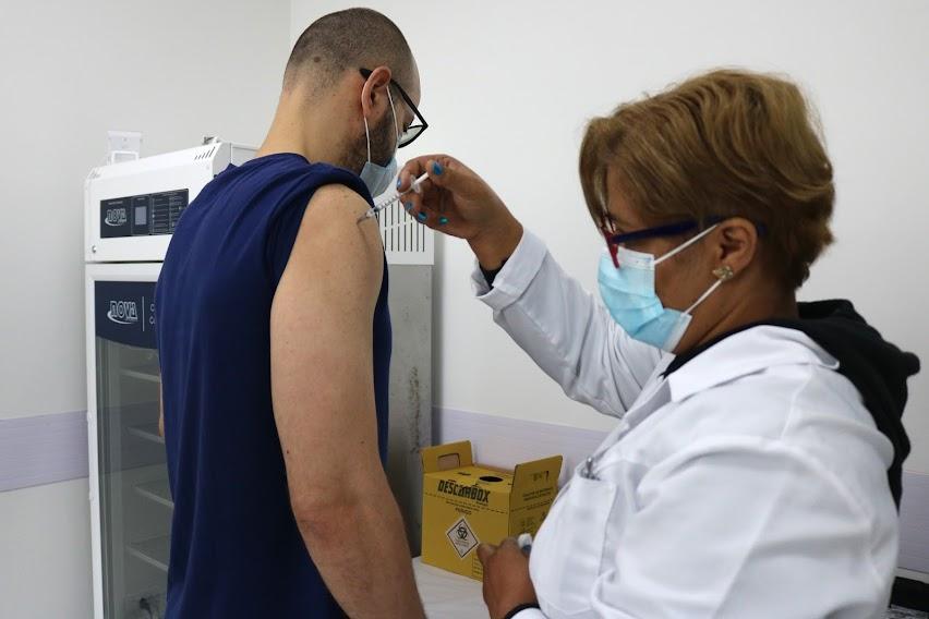 mulher vacina homem que está com a manga da camiseta suspensa. #paratodosverem