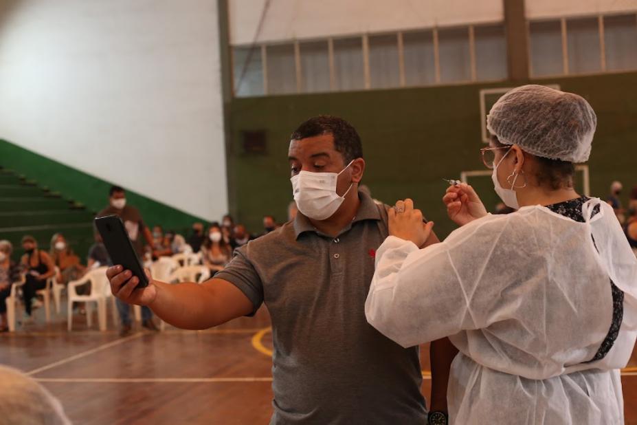 Enfermeira aplica vacina em homem que tira selfie #paratodosverem