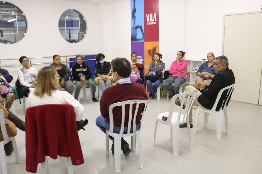 mulheres estão sentadas em cadeiras em formato de roda. Há também dois homens. #paratodosverem