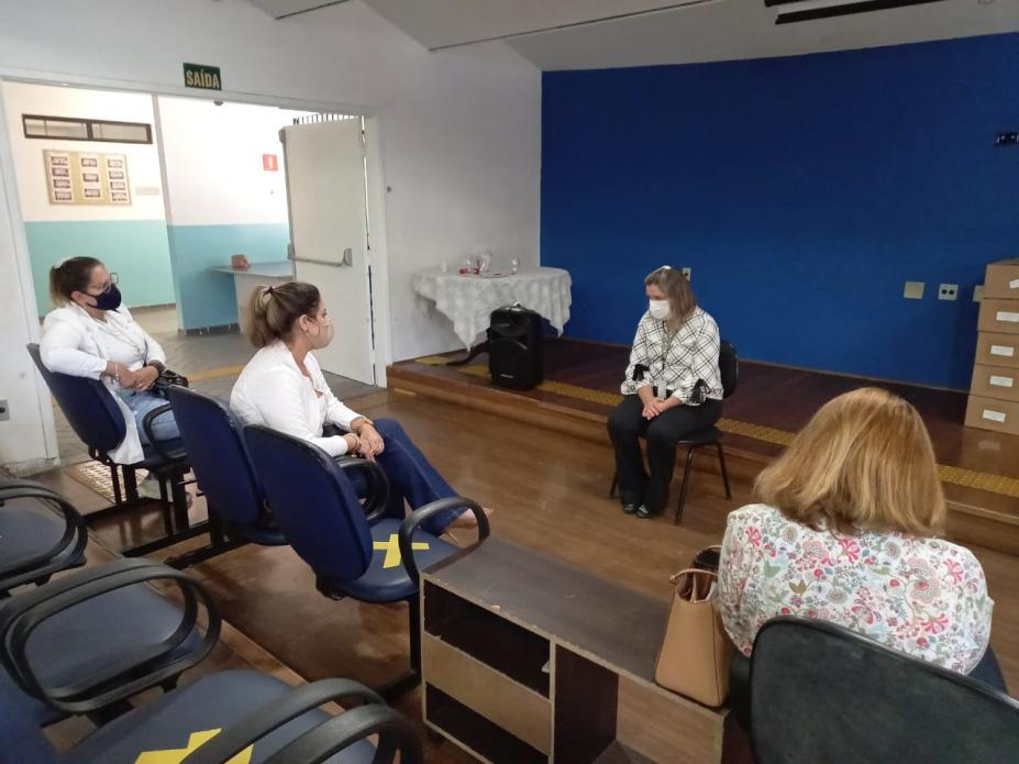 Auditório escolas com quatro pessoas conversando. Elas estão mantendo distanciamento umas das outras. #paratodosverem