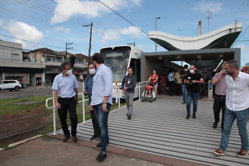 Vários homens em estação do VLT com modal parado à esquerda. #paratodosverem