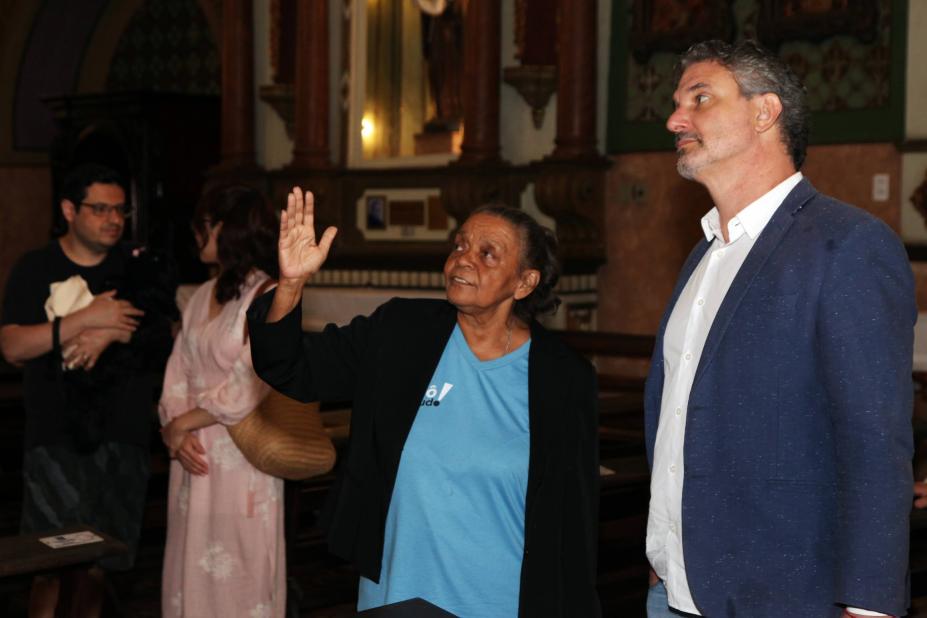 mulher uniformizada mostra ambiente de igreja para homem. #paratodosverem