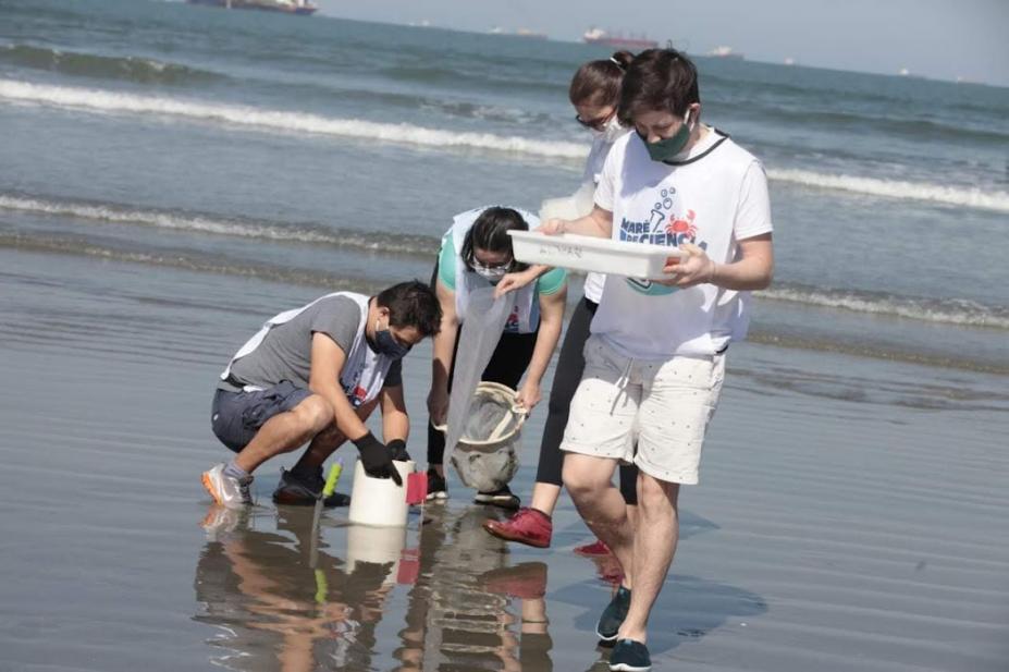 pessoas colhem e observam lixo encontrado no mar #paratodosverem
