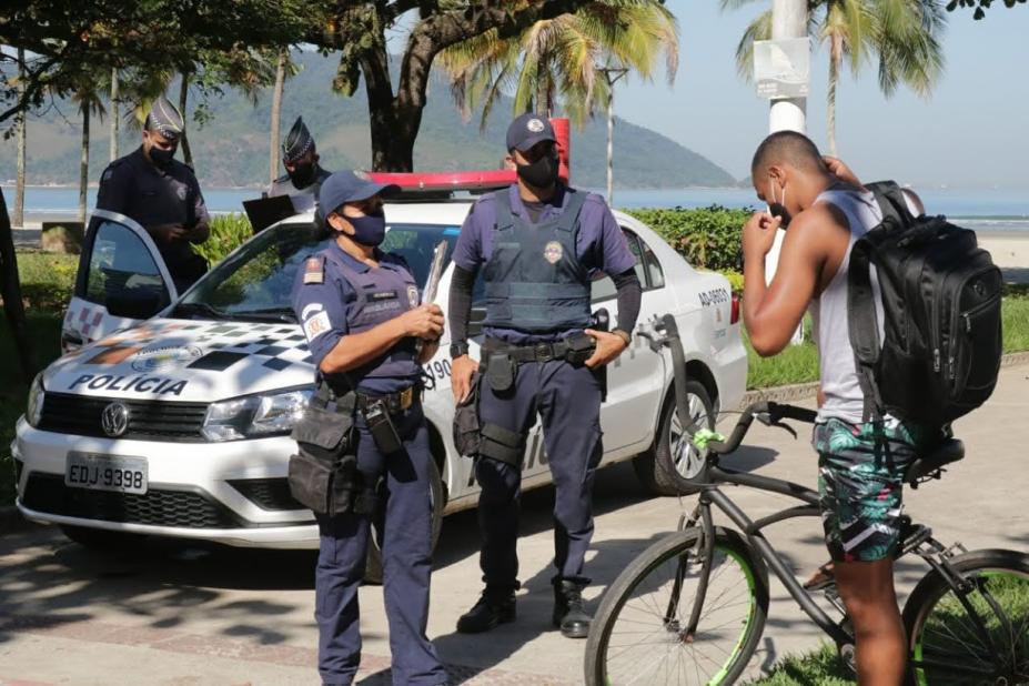 Guardas municipais ao lado de viatura orientam ciclista a colocar máscara. #Paratodosvem