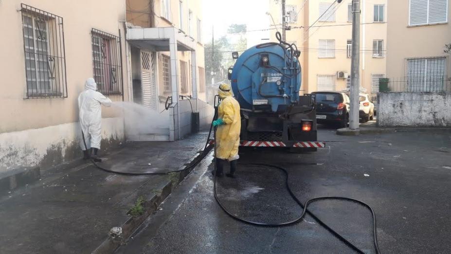 atrás de caminhão, dois homens limpam calçada #paratodosverem 