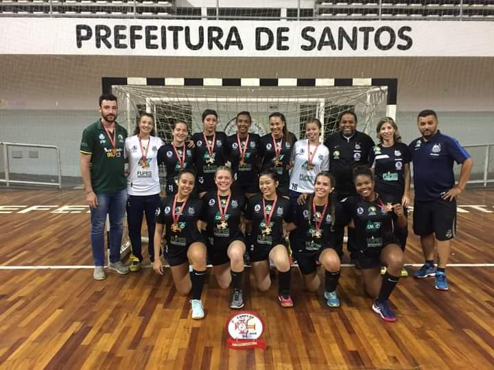 atletas com medalhas posam para foto em quadra #paratodosverem