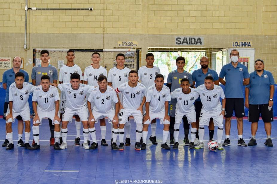 atletas usando uniforme branco , em duas fileiras, abraçados , em uma quadra #paratodosverem