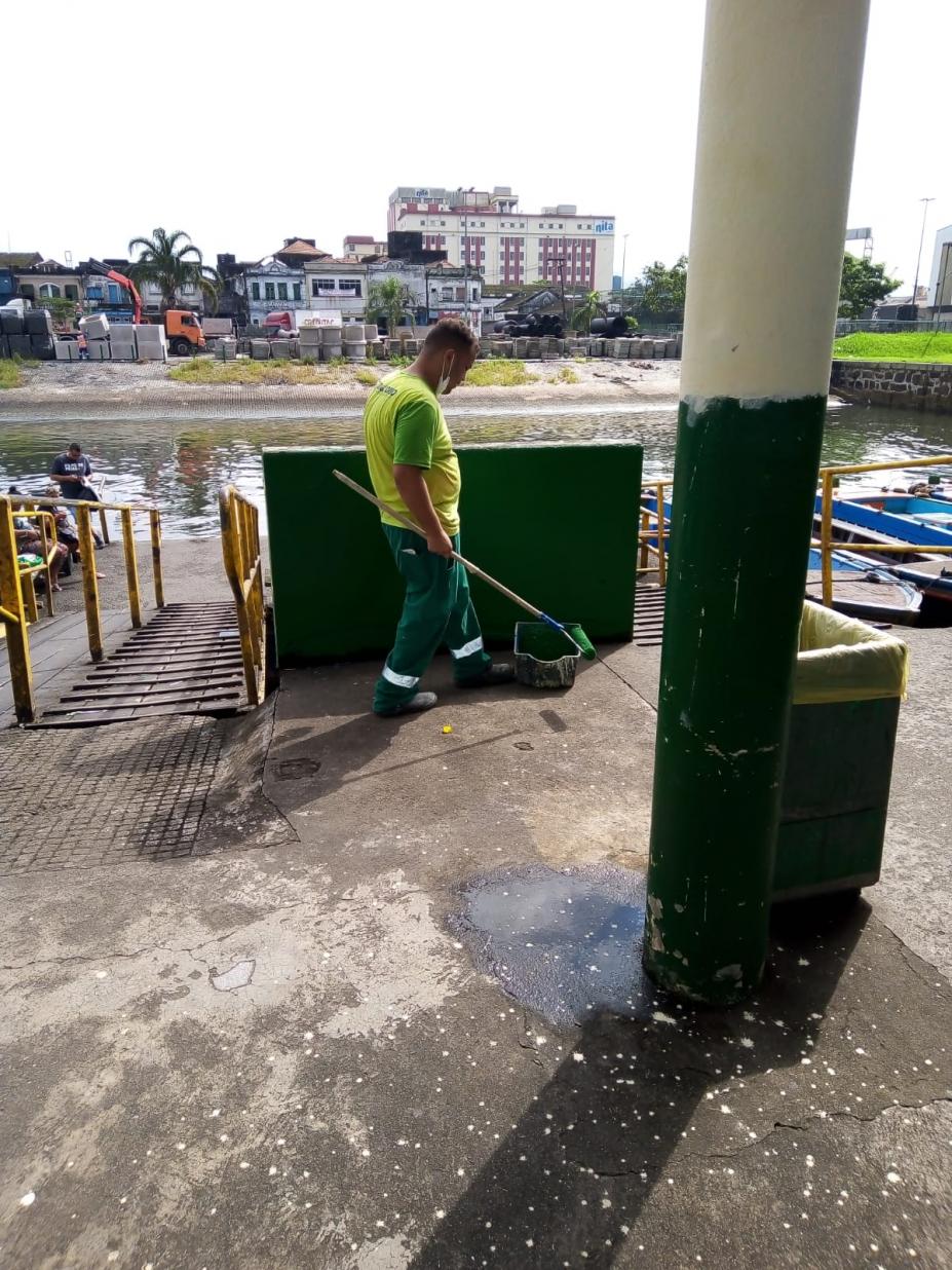 funcionário vestido de verde segura pincel grande de pintura #paratodosverem