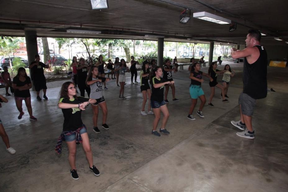 pessoas dançando em frente e um homem #paratodosverem