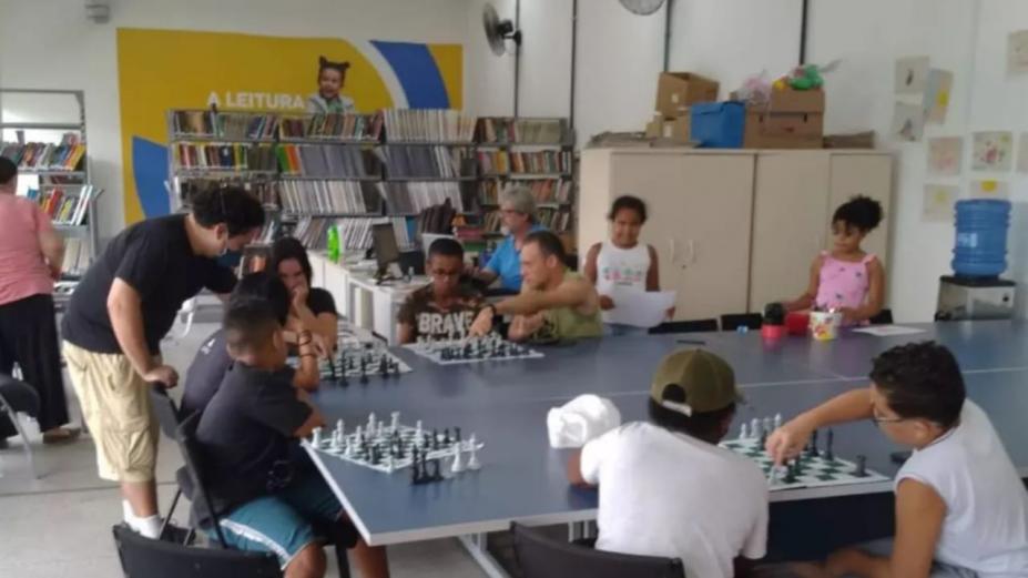 crianças jogando xadrez dentro de biblioteca #paratodosverem