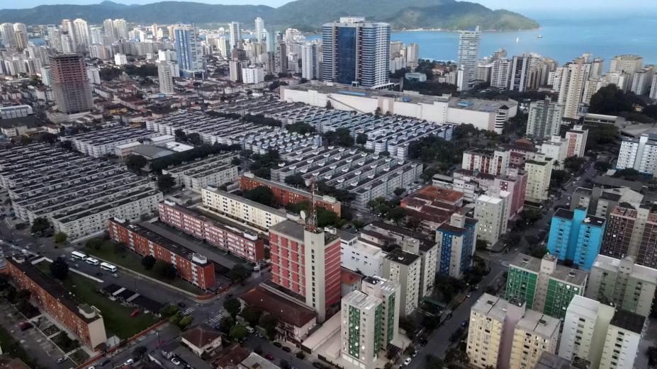vista aérea de bairro com muitos prédios e o mar ao fundo. #paratodosverem 