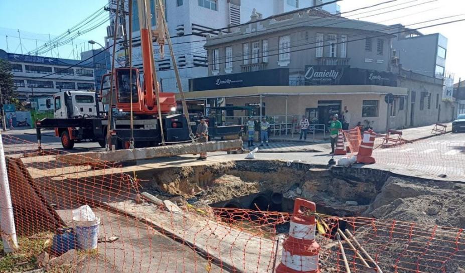 obra na via com buraco grande e caminhão ao lado levantando uma cobertura #paratodosverem