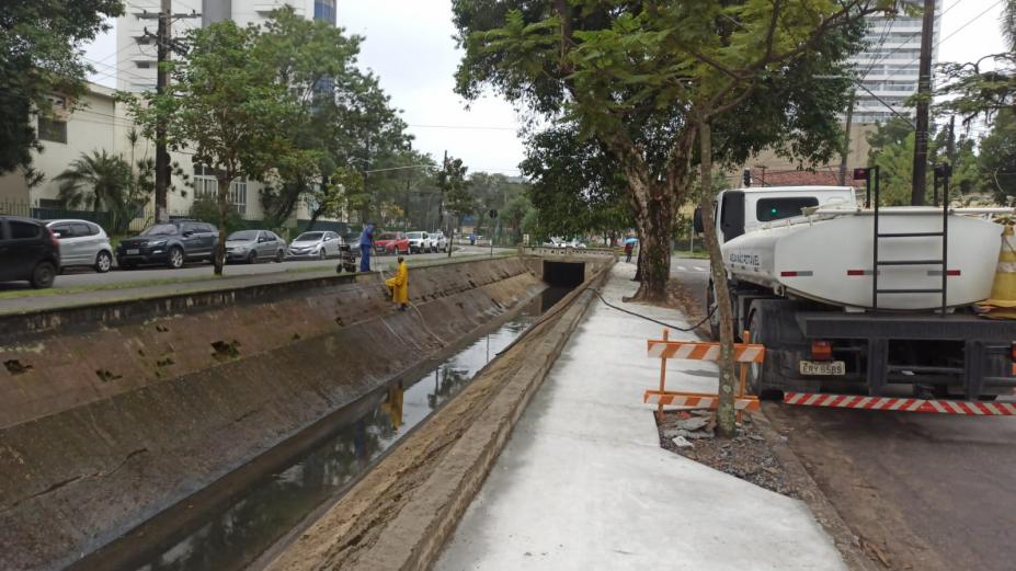 homem trabalhando no canal e calçada com concreto e caminhão ao lado #paratodosverem