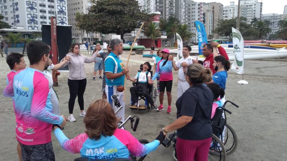 pessoas em circulo na praia de mãos dadas #paratodosverem