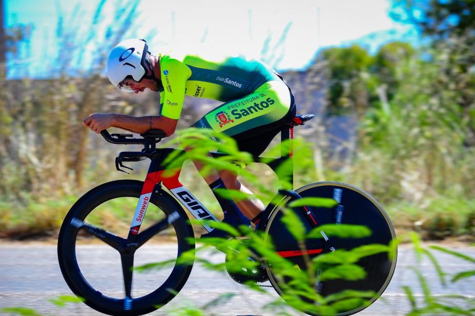 atleta em cima de bike em pista cerca de vegetação #paratodosverem