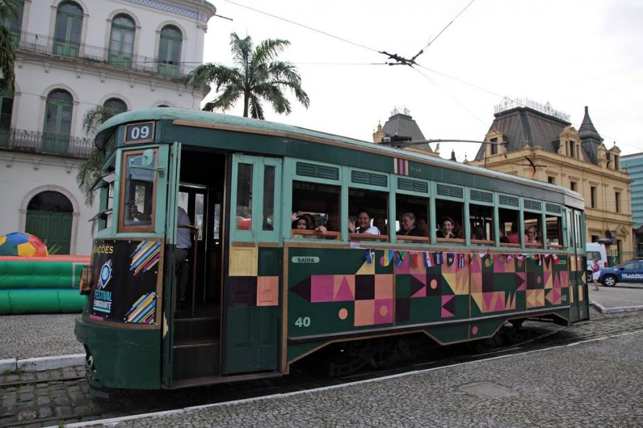 bonde com pessoas dentro circula por rua no centro histórico #paratodosverem