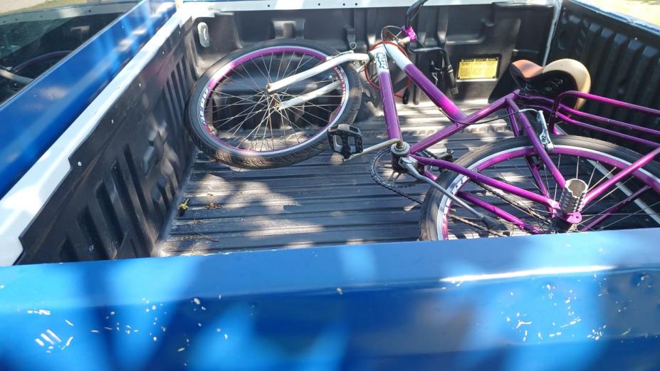 bicicleta cor de rosa está dentro de caçamba de veículo. #paratodosverem