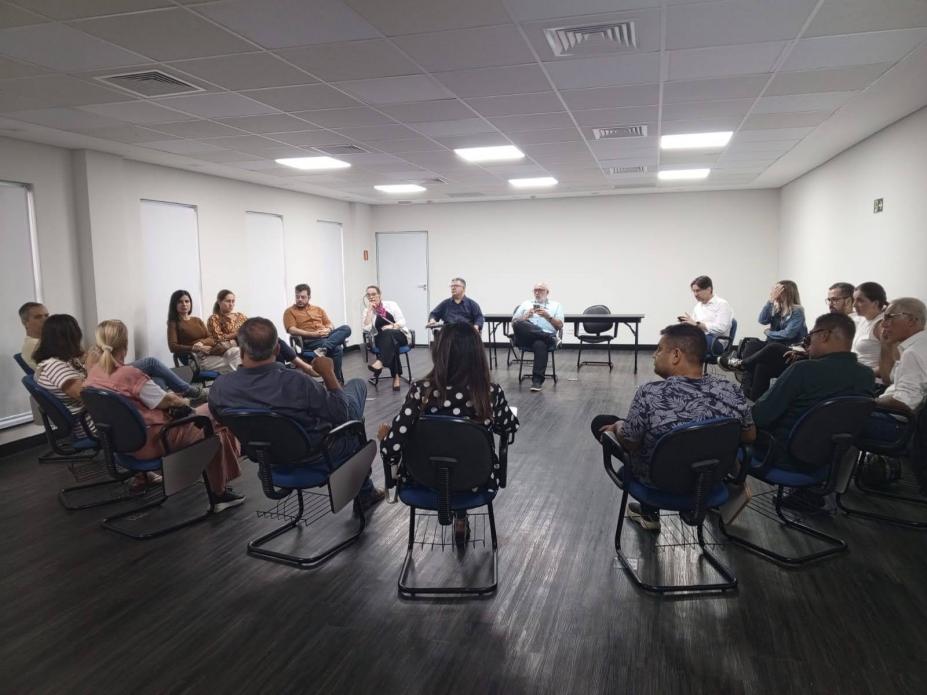pessoas sentadas e reunidas em roda em salão. #paratodosverem 