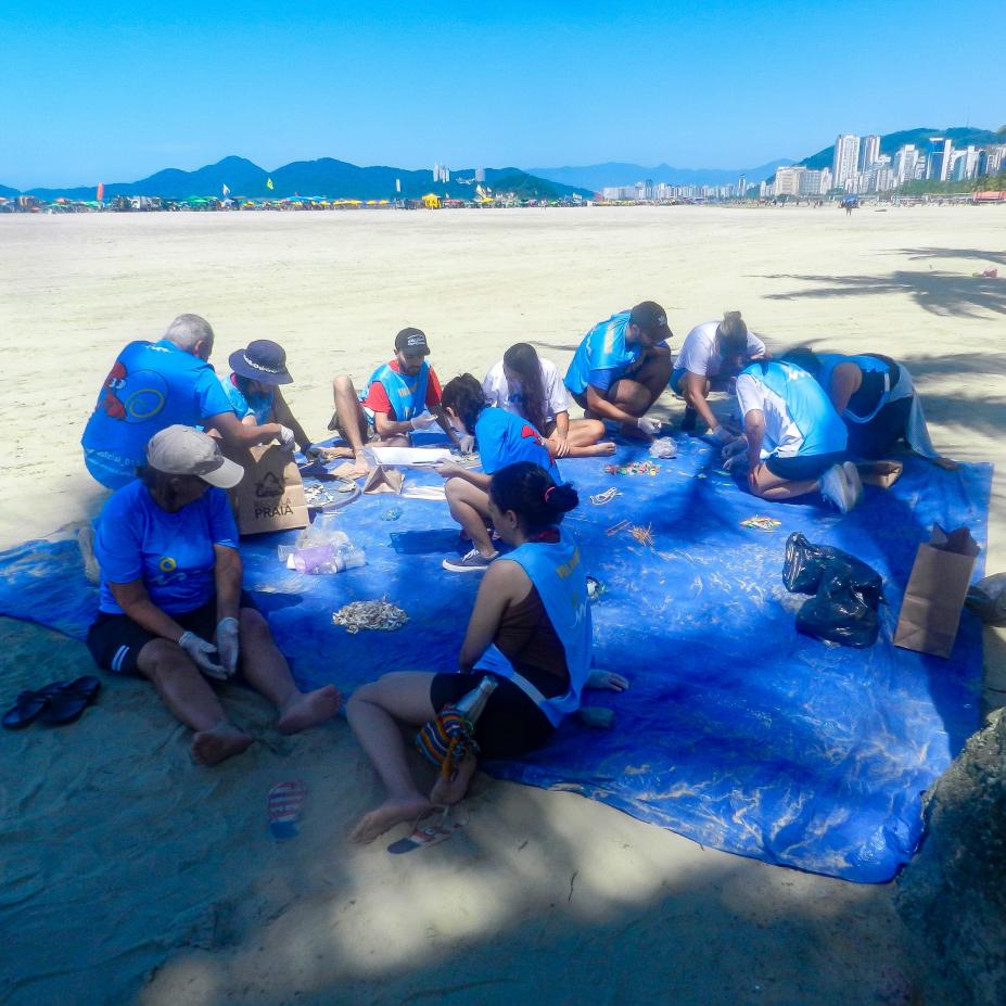 pessoas colhendo lixo na praia #paratodosverem