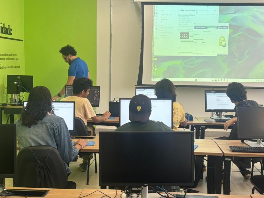 alunos em sala de aula com telão e professor. #paratodosverem