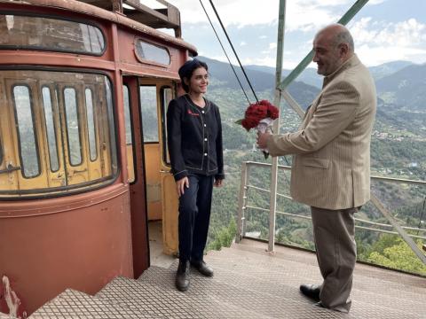 homem dá flor para mulher com teleférico atrás